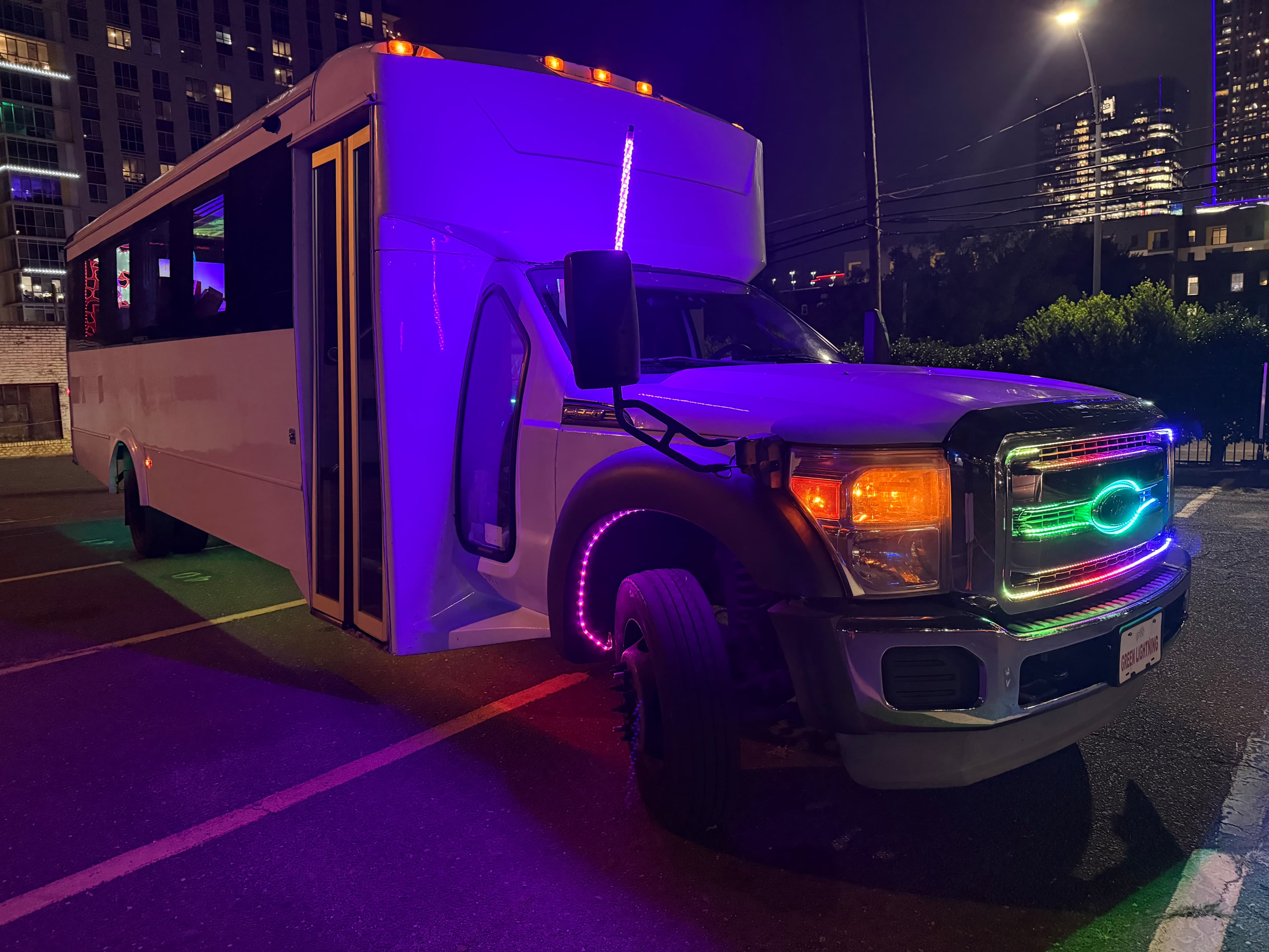 Party bus with purple LED lighting at night for Charlotte tailgate party transportation