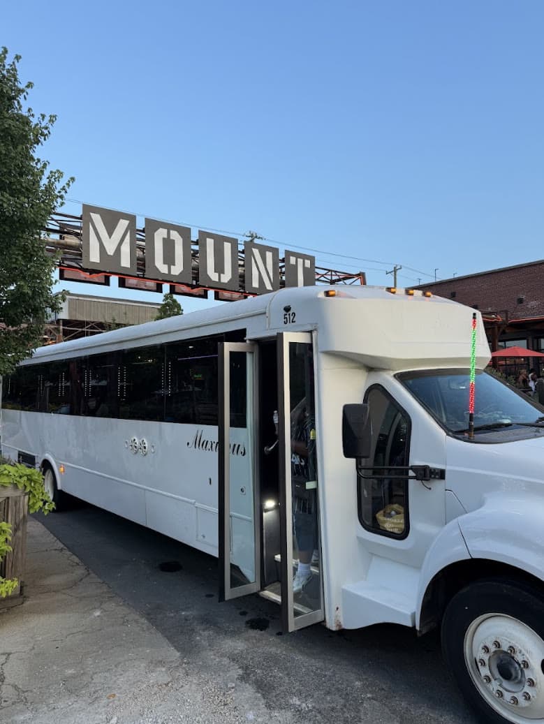 Inside The Brennan 30 passenger party bus — wraparound leather seating under the neon sign and customizable LED marquee, Charlotte NC